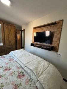 a bedroom with a bed with a flat screen tv on the wall at Casa Praia da Fonte in Guarapari