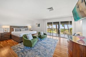 a bedroom with a bed and two chairs and a television at Hale Kalapu · Large Home 180° Ocean Views Walk2Beach Hale Kalapu in Kaanapali
