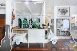 a white scooter parked in a room with a table at Shellies On The Beach - Big House in Sawtell