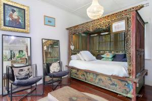 a bedroom with a canopy bed with two chairs at Shellies On The Beach - Big House in Sawtell