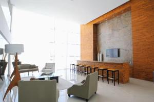 a living room with chairs and tables and a stone wall at Beachfront Apartment in Mazatlán