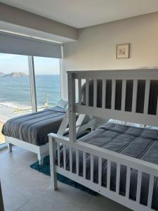 two beds in a bedroom with a view of the ocean at Beachfront Apartment in Mazatlán +17 photos