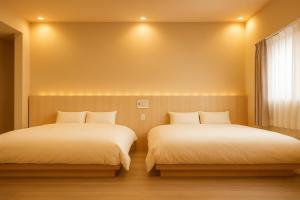 two beds sitting next to each other in a room at 滋庵 jian okayama in Okayama