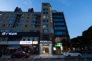Un edificio alto con coches aparcados delante. en 象往酒店一情侣路海滨泳场店, en Zhuhai
