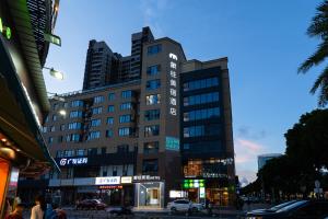 Un edificio alto en una calle de la ciudad por la noche. en 象往酒店一情侣路海滨泳场店, en Zhuhai