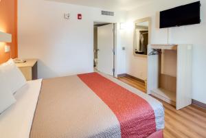 a hotel room with a bed and a flat screen tv at Motel 6-Lenexa, KS - Kansas City Southwest in Lenexa
