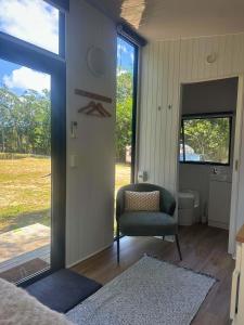 a living room with a chair and a window at The Dacious by Tiny Away in Midgenoo +3 photos