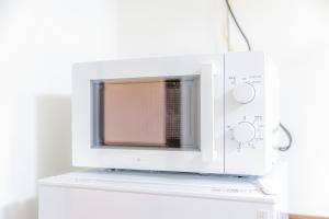 Un four micro-ondes est installé au-dessus d'une armoire blanche. dans l'établissement オーシャンビュー窓から見える景色を思い出に the琉球タワー10E, à Yonabaru