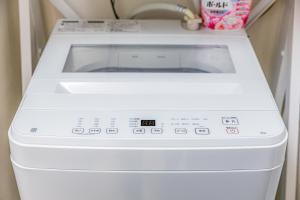 - un lave-linge et un sèche-linge blancs dans la chambre dans l'établissement オーシャンビュー窓から見える景色を思い出に the琉球タワー10E, à Yonabaru