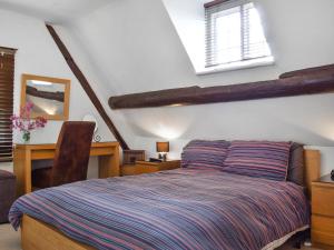 a bedroom with a bed and a desk and windows at White Cottages in Whitby