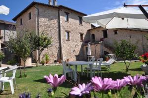 a patio with a table and an umbrella and flowers at Il Casale Di Ginetto in Cascia
