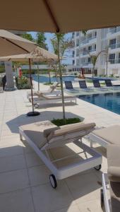 un gruppo di sedie a sdraio e un ombrellone accanto alla piscina di Loft BelloHorizonte vista al mar y reserva cabo tortuga a Santa Marta