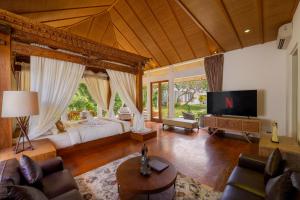 a large living room with a bed and a tv at Mahameru Uluwatu in Uluwatu