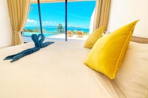 Un dormitorio con una cama con almohadas amarillas y una ventana. en Villa Sabanya Sea View, en Ban Nua
