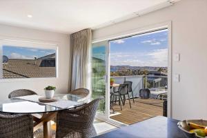 a dining room with a table and a balcony at Rainbow Haven Where family time meets Lake time in Coffs Harbour