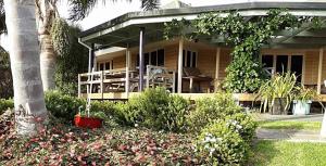 a house with a porch and a palm tree at Matai Whetū - Stargazer Tutukaka in Tutukaka +9 photos