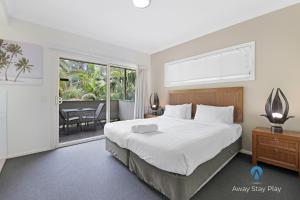 a bedroom with a large bed and a balcony at Diggers Beach Oasis in Kororo Basin