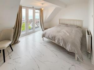 a white bedroom with a bed and a window at Oasis in Hythe