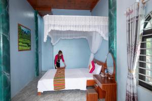 a woman sitting on a bed in a room at Tuấn Tú Homestay in Làng Bang