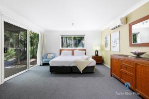 a bedroom with a bed and a sliding glass door at Diggers Beach Studio in Kororo Basin
