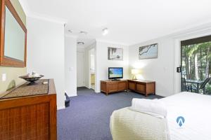 a bedroom with a bed and a desk and a television at Diggers Beach Studio in Kororo Basin