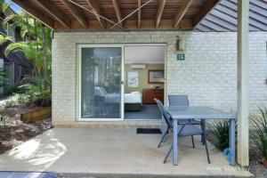 a patio with a table and chairs and a bedroom at Diggers Beach Studio in Kororo Basin