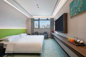une chambre avec un lit blanc et une télévision à écran plat dans l'établissement 上海艾菲花园酒店The Garden F, à Shanghai