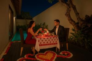 Un hombre y una mujer sentados en una mesa con copas de vino. en Anari Villas Kuta, en Legian 39 fotos más