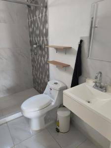a white bathroom with a toilet and a sink at Comfortable apartment with pool and wifi in Puerto Vallarta