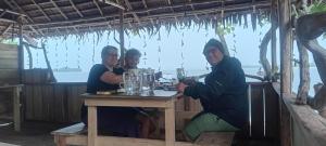 a group of three people sitting at a table at Naviza Homestay in Kepulauan Fam