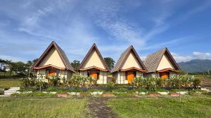 eine Reihe von Häusern mit Spitzdächern auf einem Feld in der Unterkunft Teras Alam in Karangjati