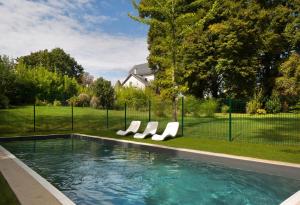 a swimming pool with lounge chairs in a yard at Le Monde de Charlie - Les Cabanes in Bellerive-sur-Allier