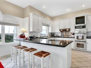 a kitchen with white cabinets and bar stools at Oceanfront Dream Home Spa Pool Pet Friendly in North Topsail Beach