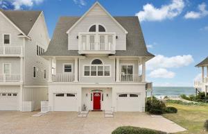 a white house with a red door and the ocean at Oceanfront Dream Home Spa Pool Pet Friendly in North Topsail Beach