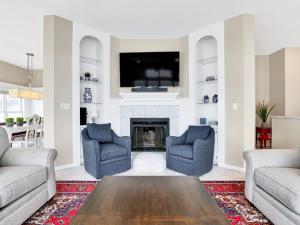 a living room with two blue chairs and a fireplace at Oceanfront Dream Home Spa Pool Pet Friendly in North Topsail Beach