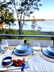 a table with plates and wine glasses and strawberries on it at The Chill - Your Dreamy Waterfront Escape in Sanctuary Point