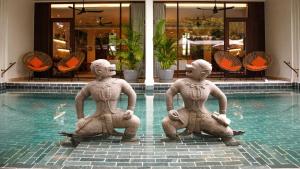 three statues sitting in the water in front of a pool at FCC Angkor by Avani in Siem Reap +69 photos