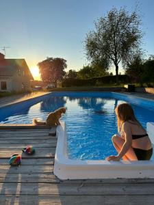 a woman and a dog sitting next to a swimming pool at Resta farm bondgårdshotell in Örsundsbro