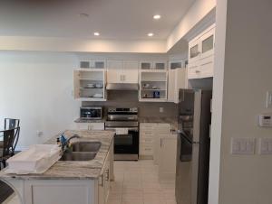 a kitchen with white cabinets and a stainless steel refrigerator at Modern 3BR Home Near Niagara Falls & Welland Canal in Welland +12 photos