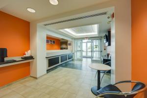 uma cozinha com paredes cor de laranja e uma mesa e cadeiras em Motel 6-Brampton, ON - Toronto em Brampton