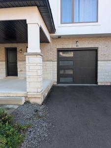a garage door in a brick house with a driveway at Modern 3BR Home Near Niagara Falls & Welland Canal in Welland