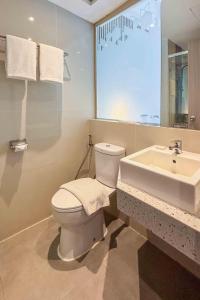 a bathroom with a white toilet and a sink at Oakwood Merdeka Bandung in Bandung