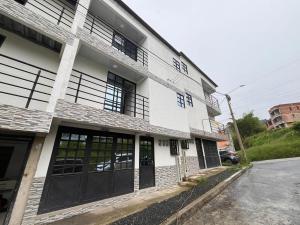 a white building with black doors on a street at Bulevar Santa Rosa, apartamento nuevo y acogedor in Santa Rosa de Cabal