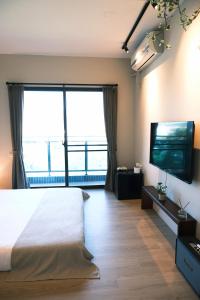 a bedroom with a large bed and a flat screen tv at 春喃日光 Whispring Inn in Hengchun