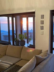 ein Wohnzimmer mit einem Sofa und großen Fenstern in der Unterkunft 1 Waterkant Luxury Renovated 3 Bedroom House in De Kelders