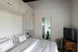 ein Schlafzimmer mit einem Bett und einem Flachbildfernseher in der Unterkunft 1 Waterkant Luxury Renovated 3 Bedroom House in De Kelders