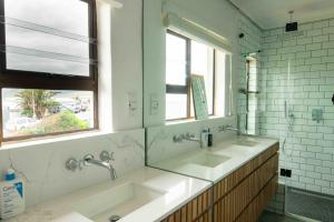 ein Badezimmer mit zwei Waschbecken und zwei Fenstern in der Unterkunft 1 Waterkant Luxury Renovated 3 Bedroom House in De Kelders + 28 Fotos