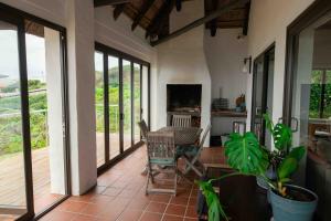 eine abgeschirmte Veranda mit einem Tisch und Stühlen in der Unterkunft 1 Waterkant Luxury Renovated 3 Bedroom House in De Kelders
