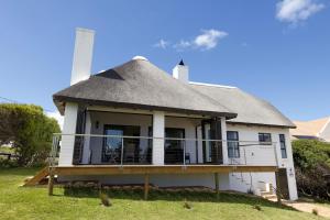 ein Haus mit einem Strohdach auf dem Gras in der Unterkunft 1 Waterkant Luxury Renovated 3 Bedroom House in De Kelders