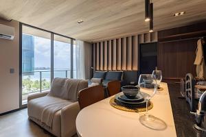 a living room with a couch and a table with wine glasses at Edifício New Time, Seu Refugio a Beira Mar de Pajuçara in Maceió